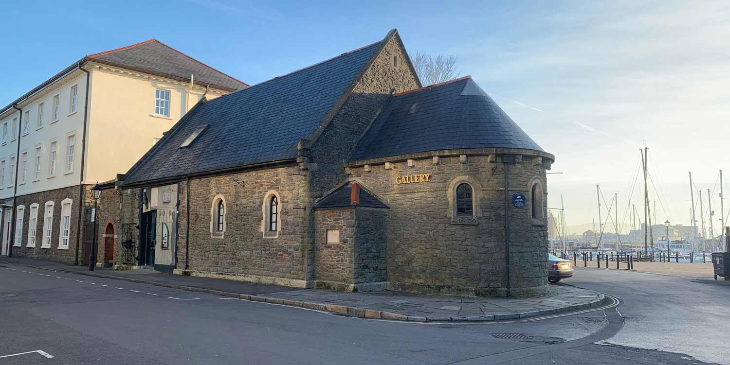 A photo of the outside of Mission Gallery on a sun day. A former seaman's mission - a type of church, with stone walls and slate roof.