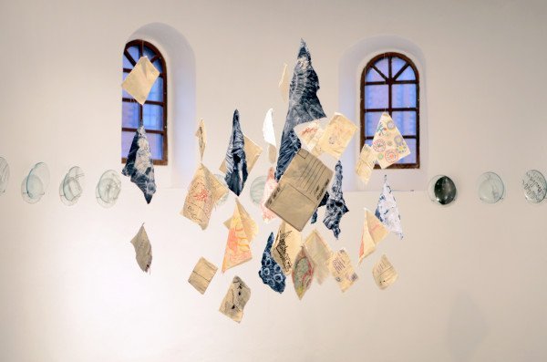 Artworks on paper hanging from ceiling as an installation in the gallery