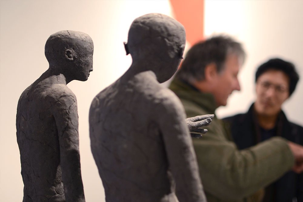 Professional Seminar. Two People talk in front of two ceramic sculptures by Claire Curneen.